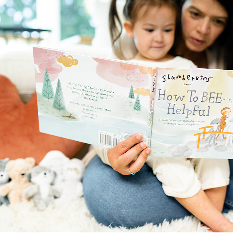 Caregiver reading the picture book How To BEE Helpful aloud to a child on her lap in a cozy room