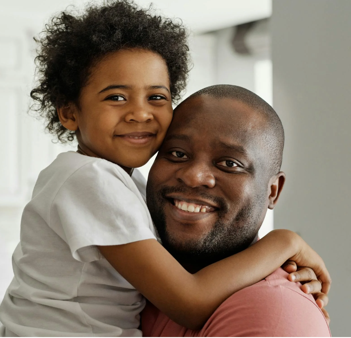 Father smiling while hugging his young child in a bright home setting