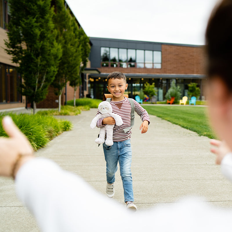 Child running to parents with Sloth in arms after their first day back-to-school.