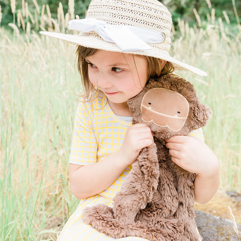 Child sitting in a field holding onto Bigfoot Snuggler