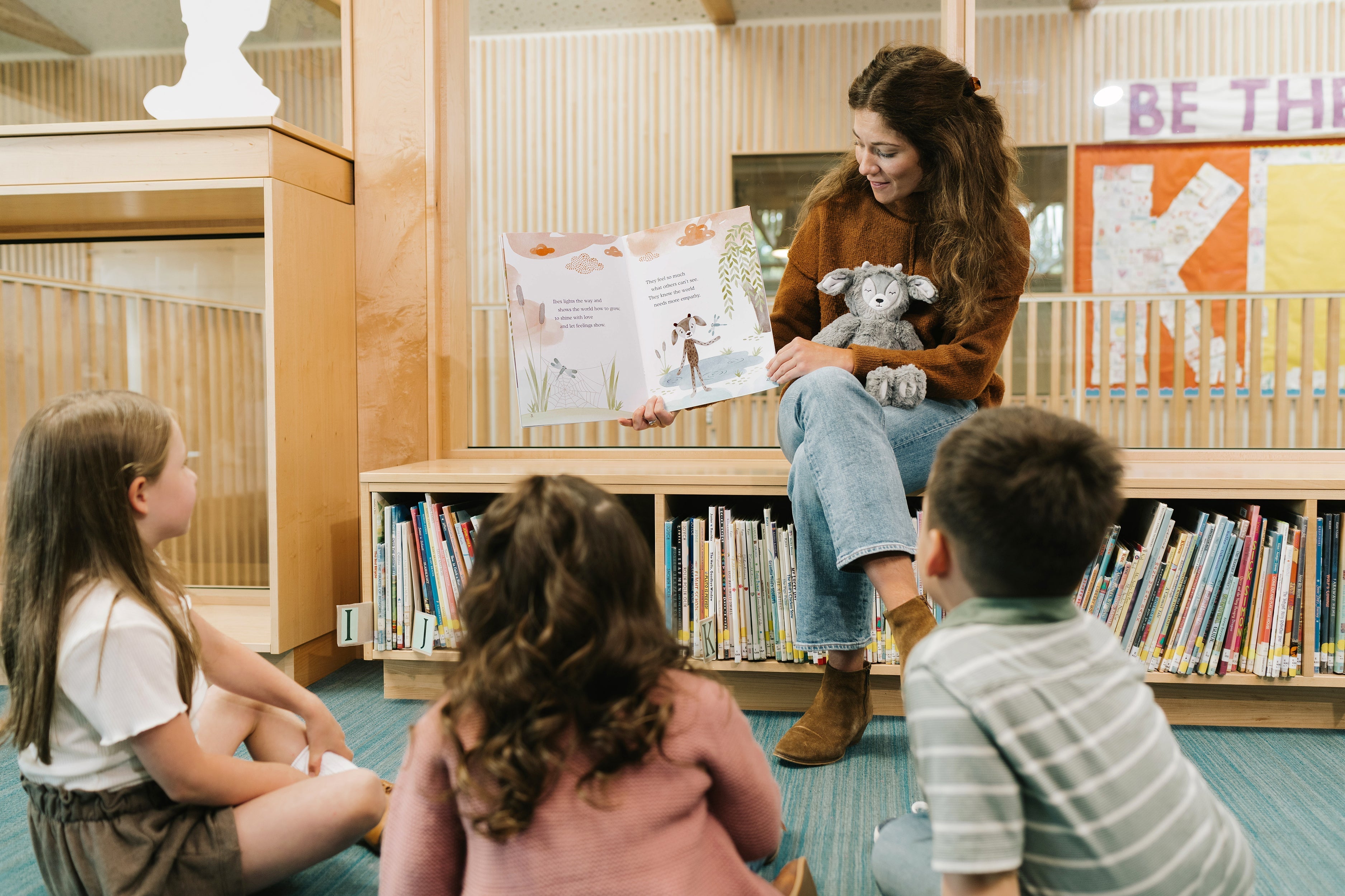 An elementary teacher leading a circle-time lesson with students using plush creatures as SEL lessons for elementary.